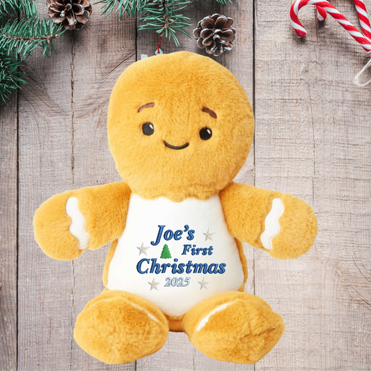Plush gingerbread toy with 'Joe's First Christmas 2023' text on a wooden background with Christmas decorations.